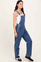 woman wearing a white tank top and blue denim overalls with a relaxed fit and side buttons