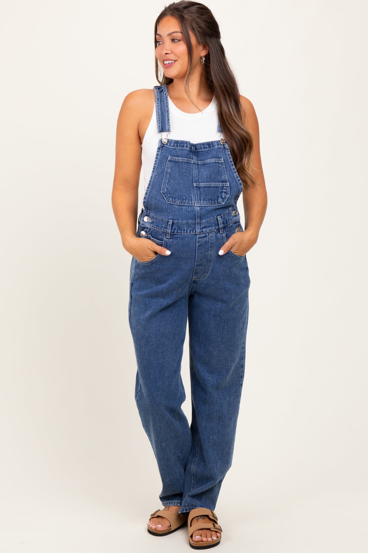 woman wearing a light blue maternity overall with adjustable straps and side pockets