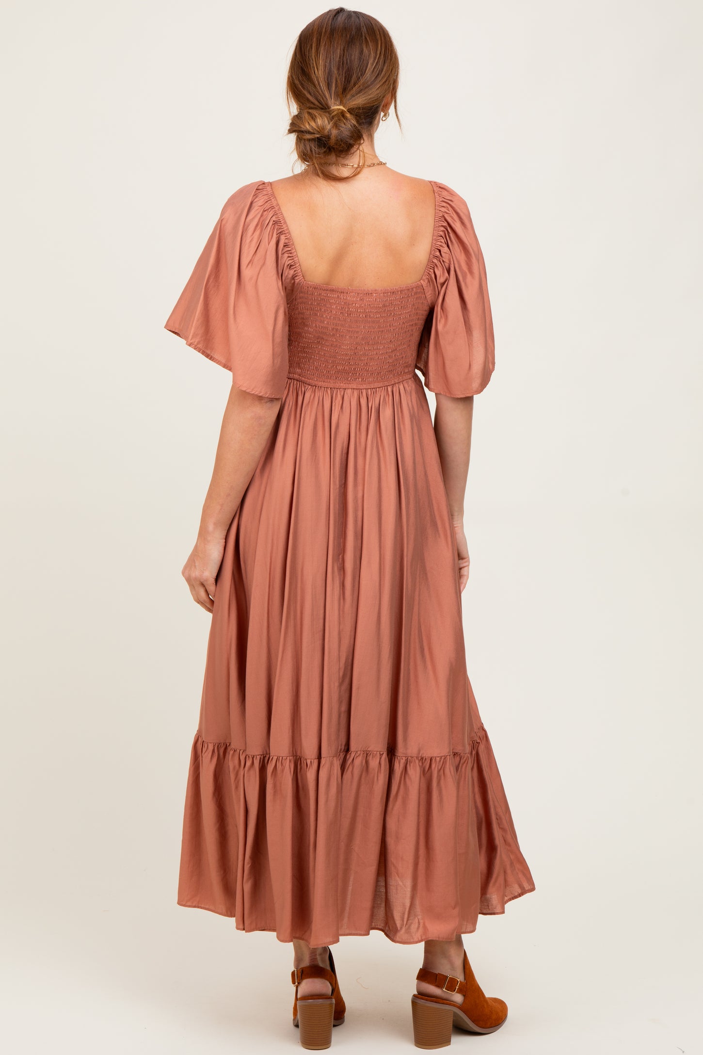 woman wearing a rust-colored maxi dress with short puff sleeves and a smocked back detail