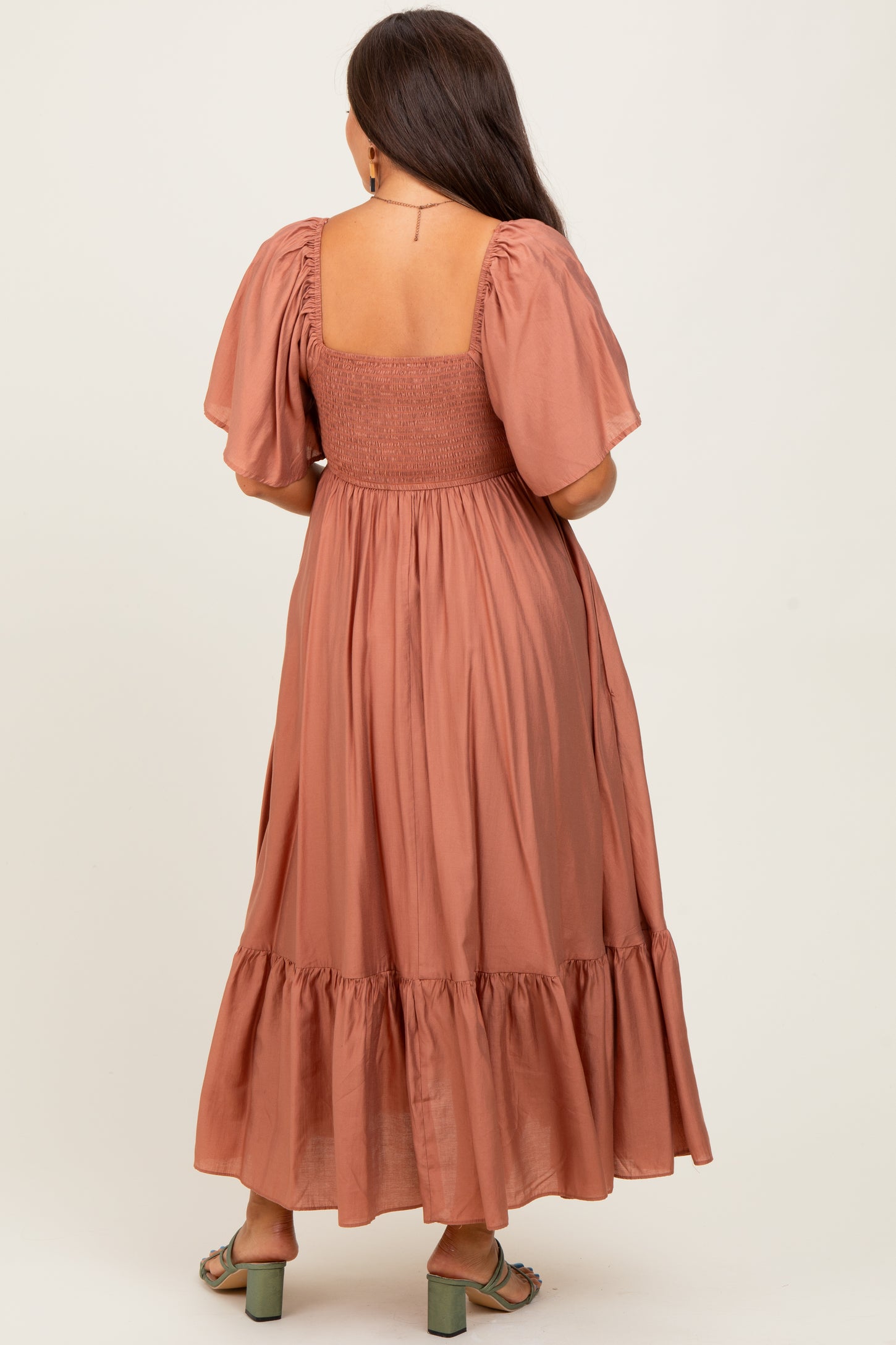 woman wearing a dusty rose maternity maxi dress with short puff sleeves and a smocked bodice