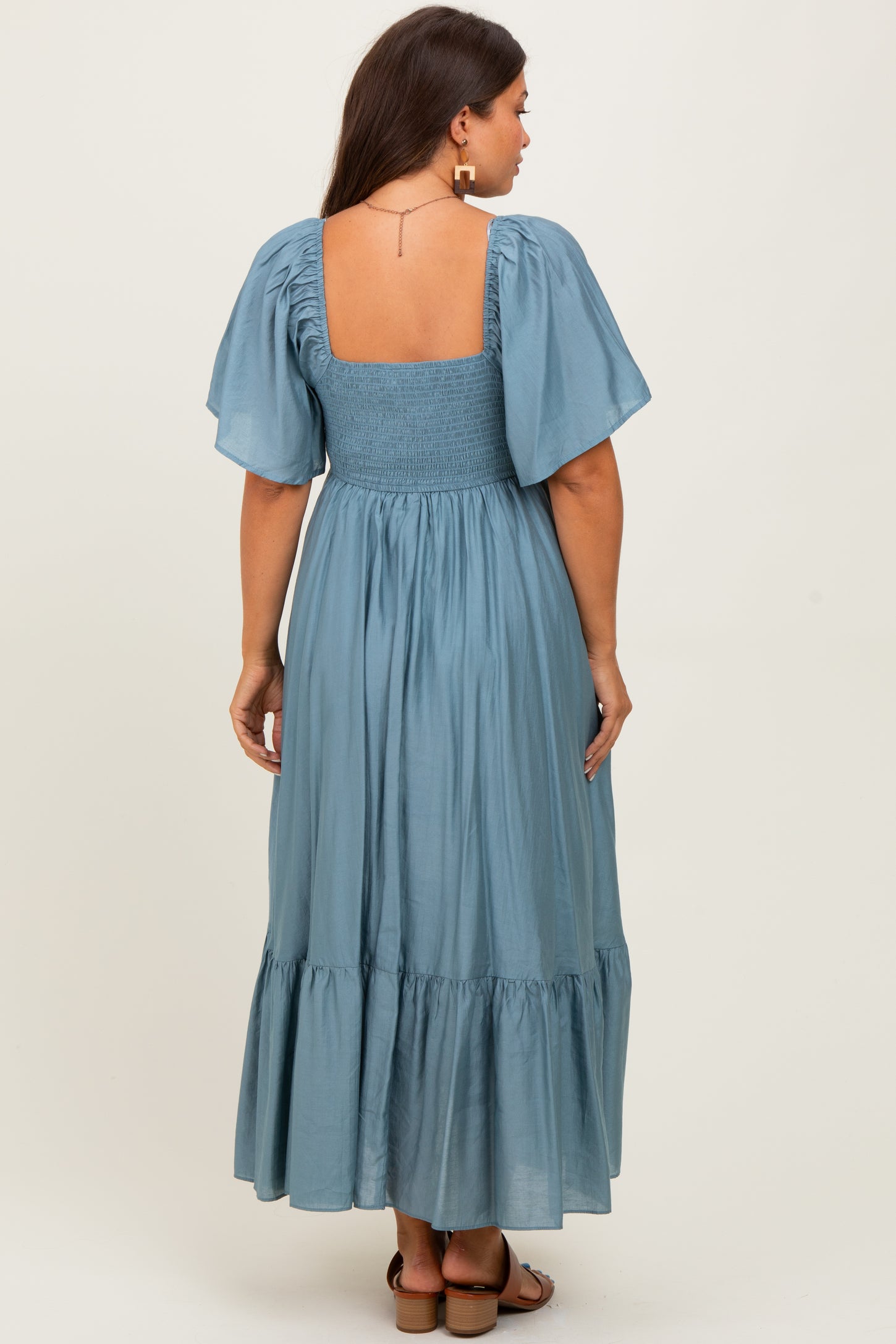woman wearing a light blue maternity maxi dress with puff sleeves and a smocked bodice, showing a baby bump