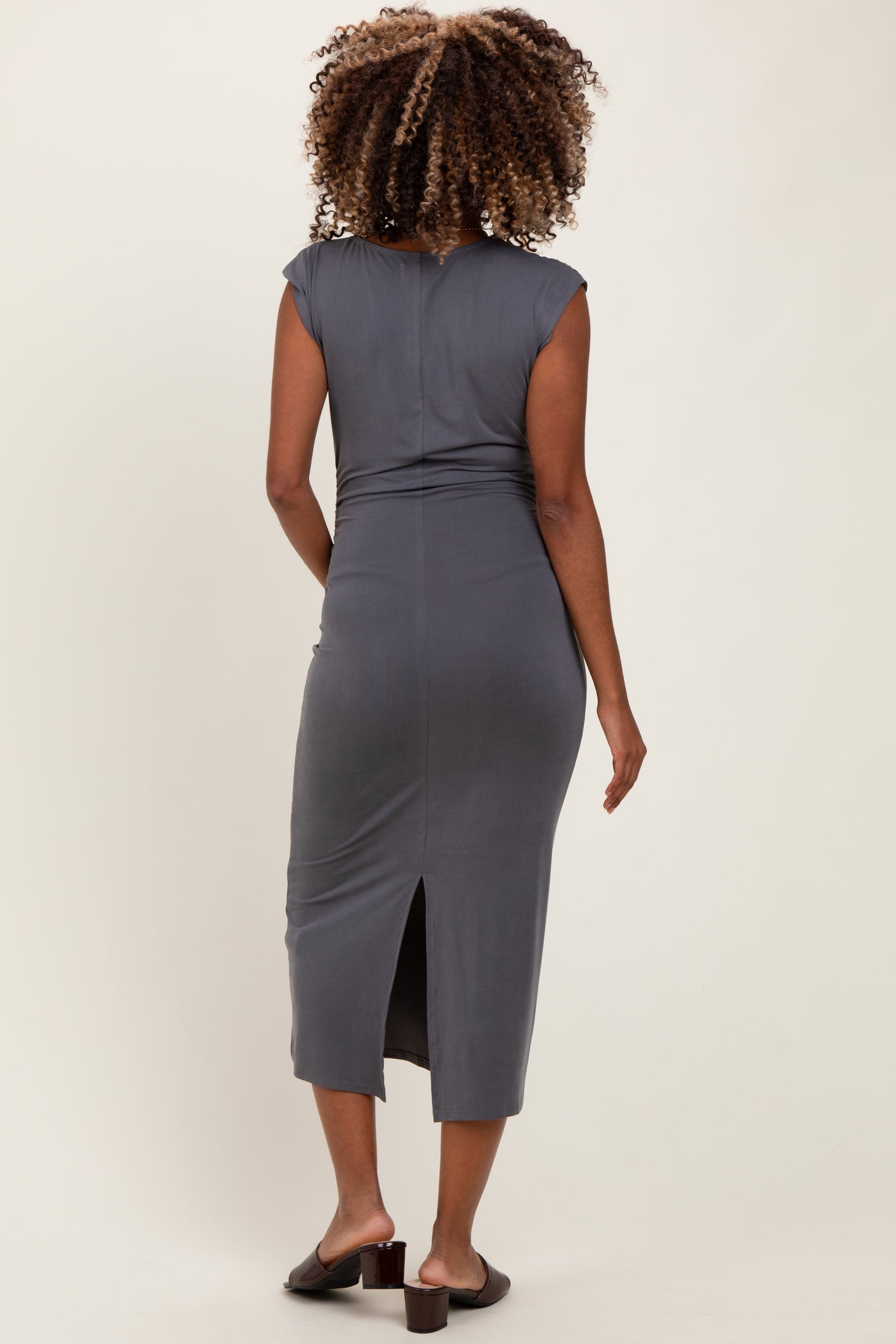 woman wearing a gray cap sleeve maternity dress with a back slit, showcasing a form-fitting style