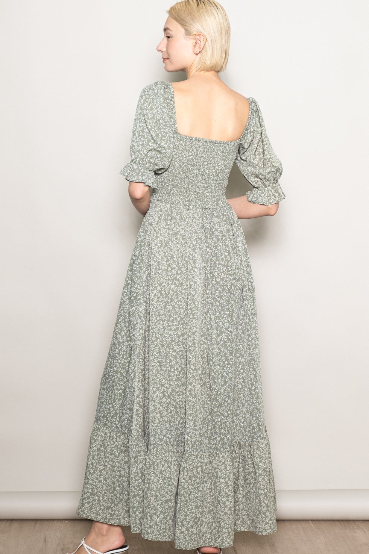 woman wearing a green floral maxi dress with puff sleeves and a square neckline, shown from the back