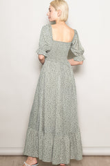 woman wearing a green floral maxi dress with puff sleeves and a square neckline, shown from the back