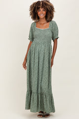 woman wearing a green floral maternity dress with puff sleeves and a ruffled hem, smiling at the camera
