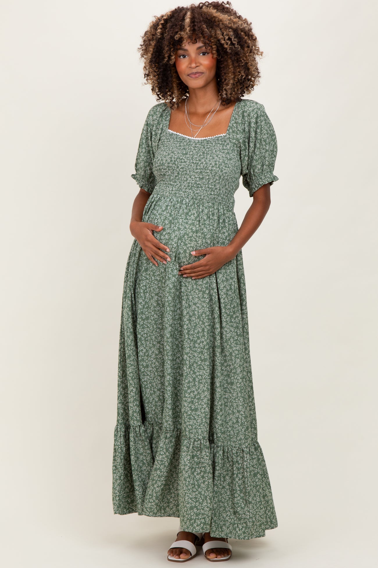 woman wearing a green floral maternity maxi dress with puff sleeves and a visible baby bump