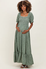 woman wearing a green floral maternity maxi dress with puff sleeves and a visible baby bump