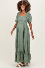 woman wearing a green floral maternity maxi dress with puff sleeves and a ruffled hem, showcasing her baby bump