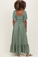 woman wearing a green floral print maternity maxi dress with puff sleeves and a tiered skirt, showing a baby bump