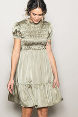 woman wearing an olive green smocked mini dress with puff sleeves and a tiered skirt