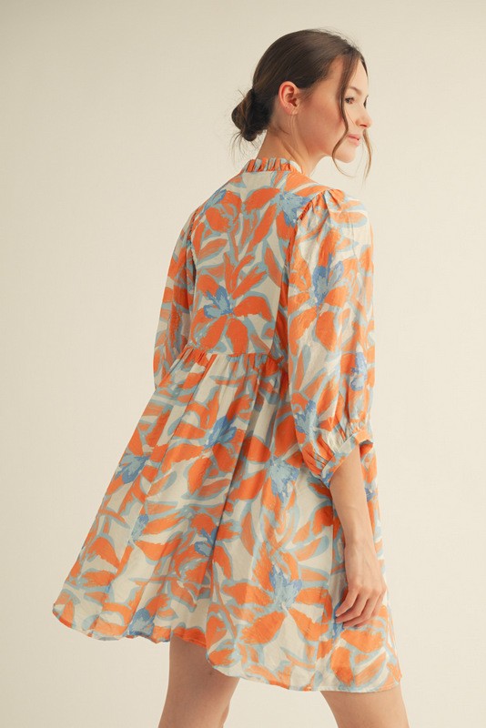 woman wearing a floral print orange and blue short sleeve dress with a flowy silhouette and gathered waistline
