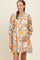 woman wearing a floral print maternity dress in orange and blue, holding her baby bump