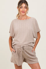 woman wearing a beige maternity short-sleeve top and matching drawstring shorts, featuring a relaxed fit and textured fabric