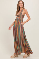 woman wearing a multi-colored striped maxi dress with a deep neckline and pockets, smiling and standing in profile