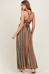woman wearing a multicolored striped maxi dress with a cross-back and tie detail at the waist