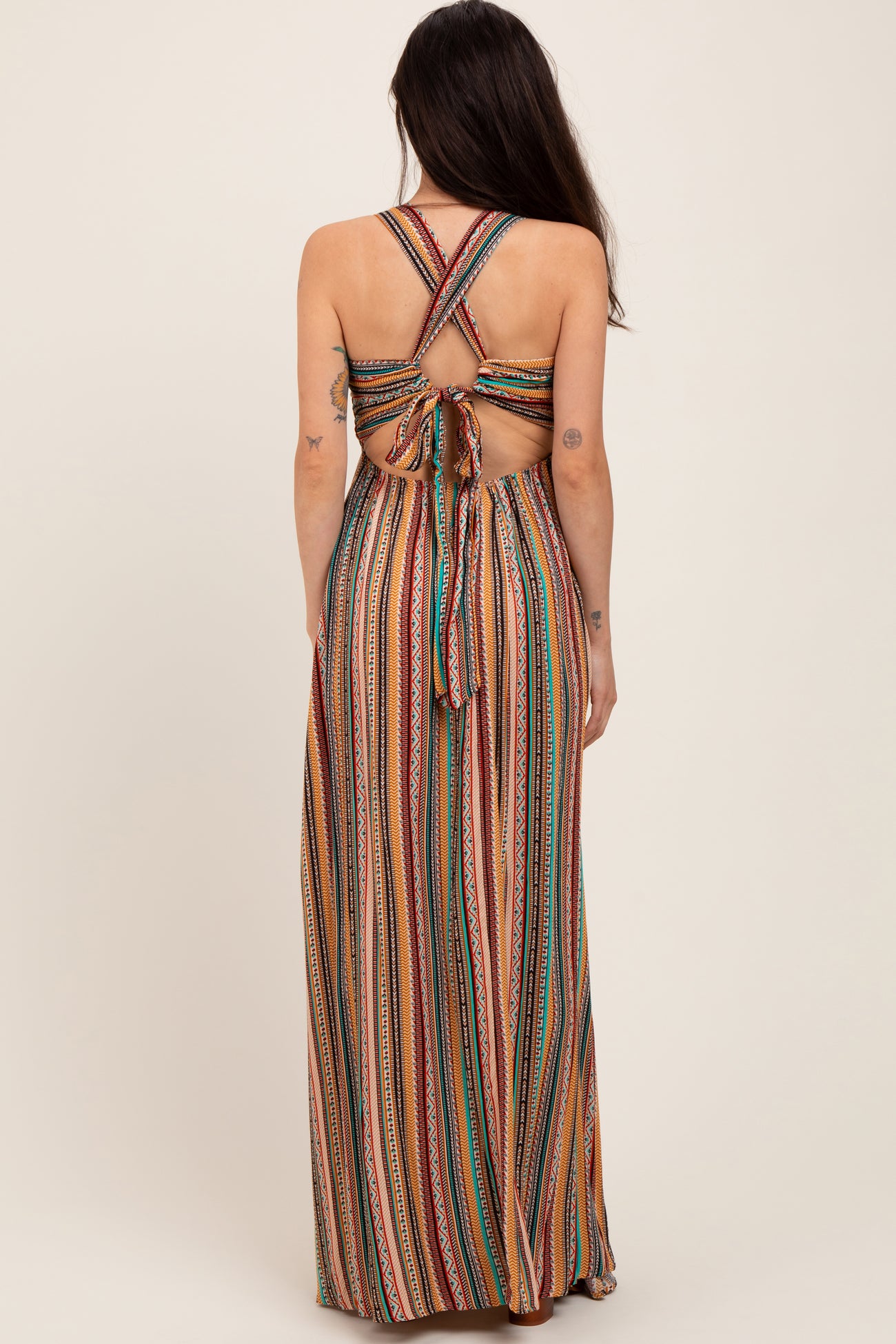 woman wearing a colorful striped maternity maxi dress with a crisscross back and tied detail