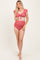woman wearing a coral maternity bikini with ruffled sleeves and high-waisted bottoms, showcasing her baby bump