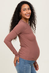 woman wearing a brown long sleeve maternity top and showing her baby bump