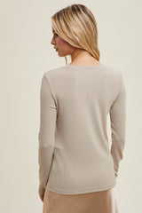 woman wearing a beige long sleeve top with a ribbed texture, viewed from the back