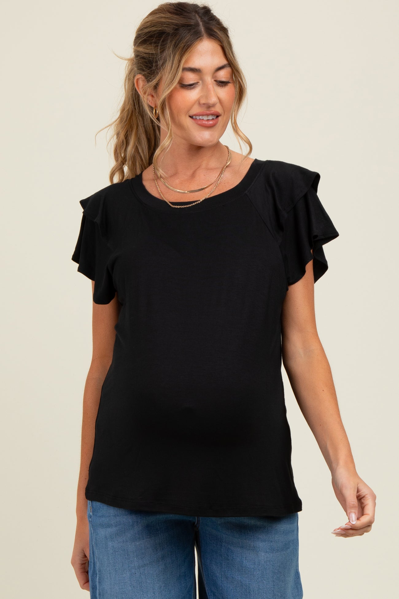 woman wearing a black maternity top with ruffled sleeves and a visible baby bump