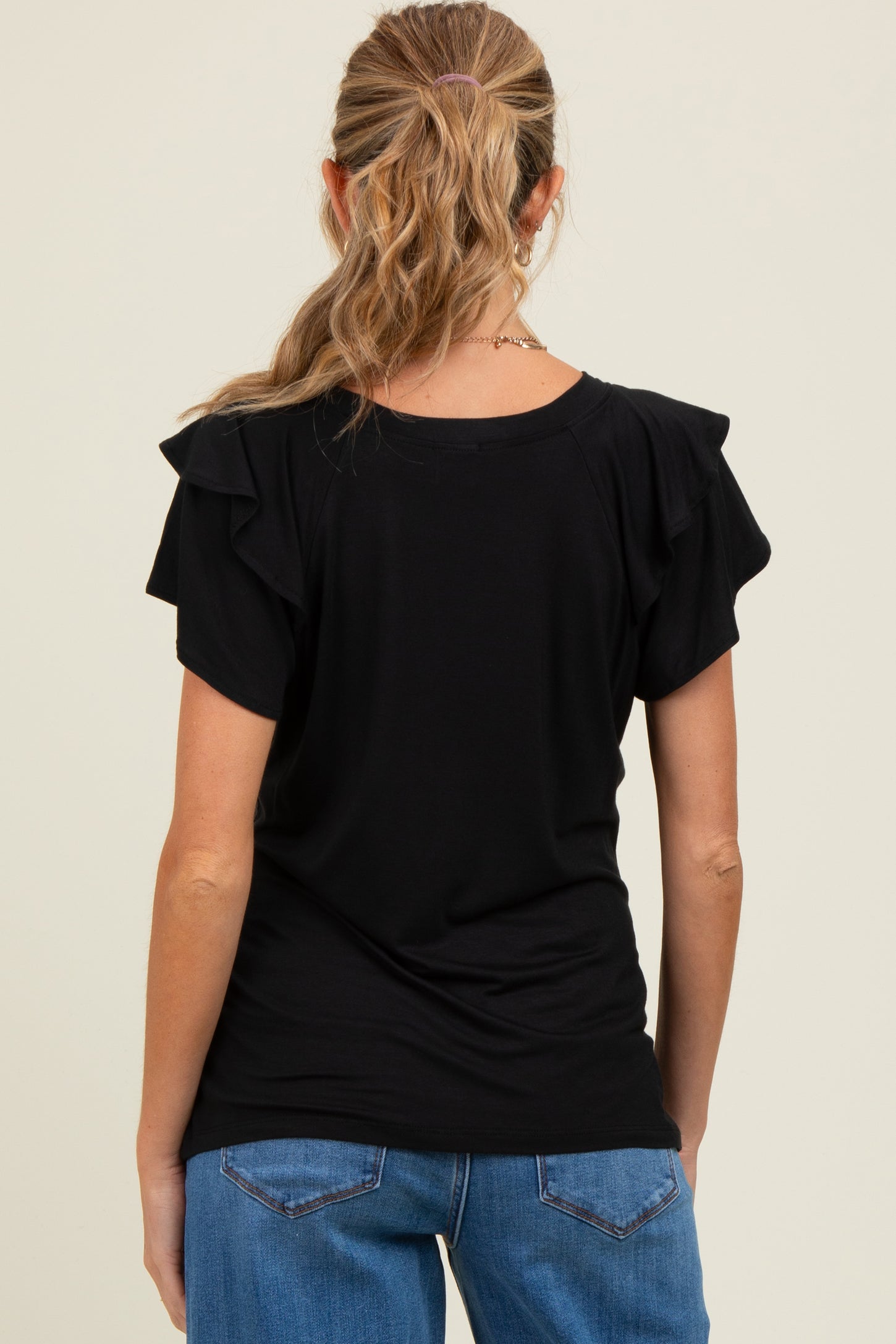 woman wearing a black short sleeve maternity top with ruffle sleeves, viewed from the back