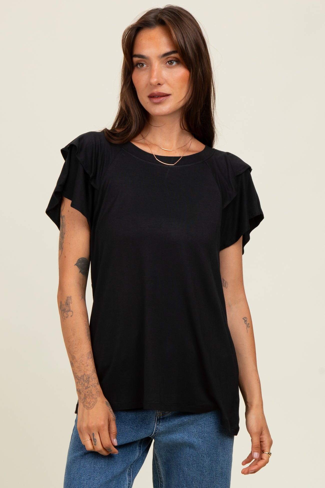 woman wearing a black short sleeve top with ruffled sleeves and a relaxed fit
