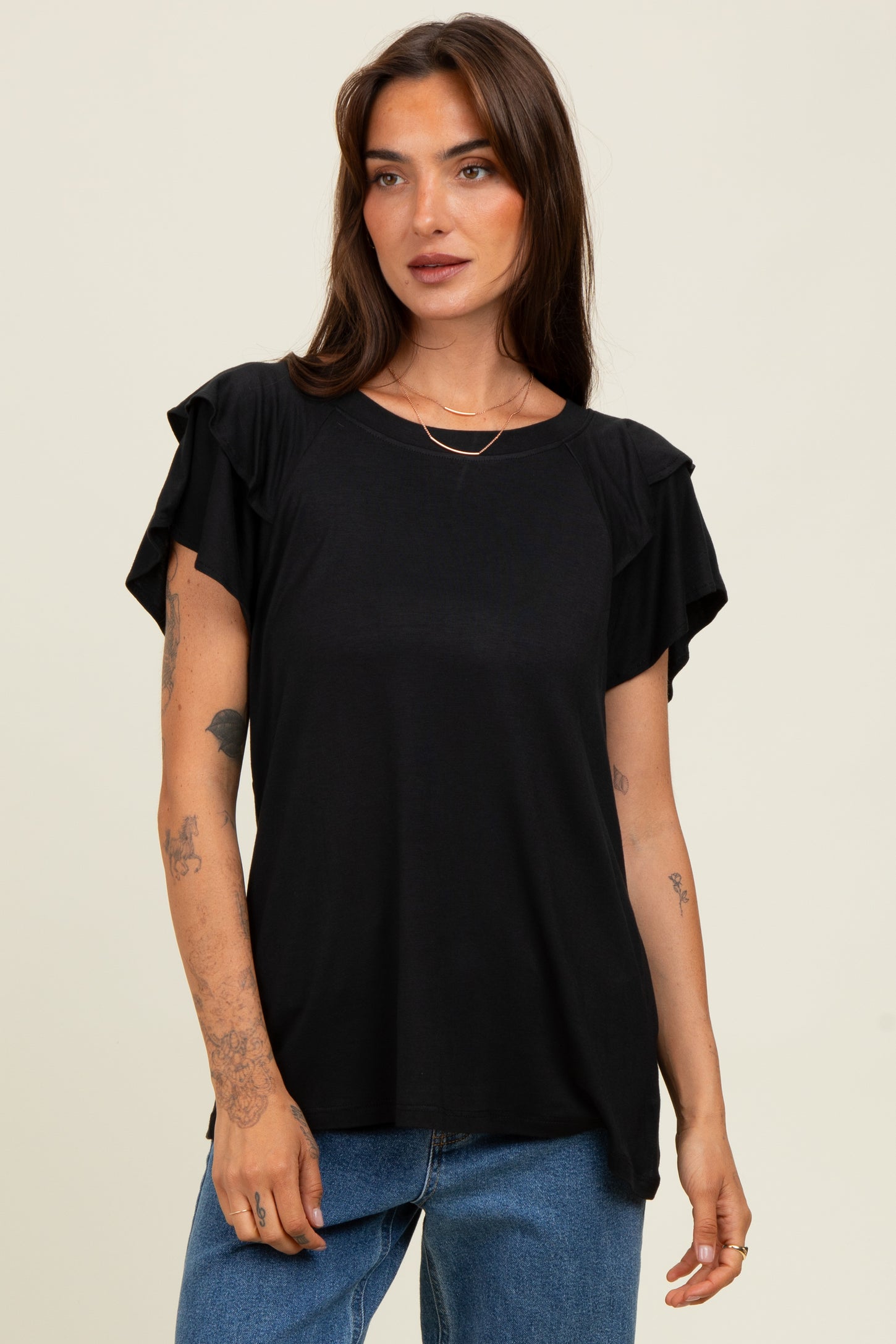 woman wearing a black short sleeve top with ruffled sleeves and a relaxed fit