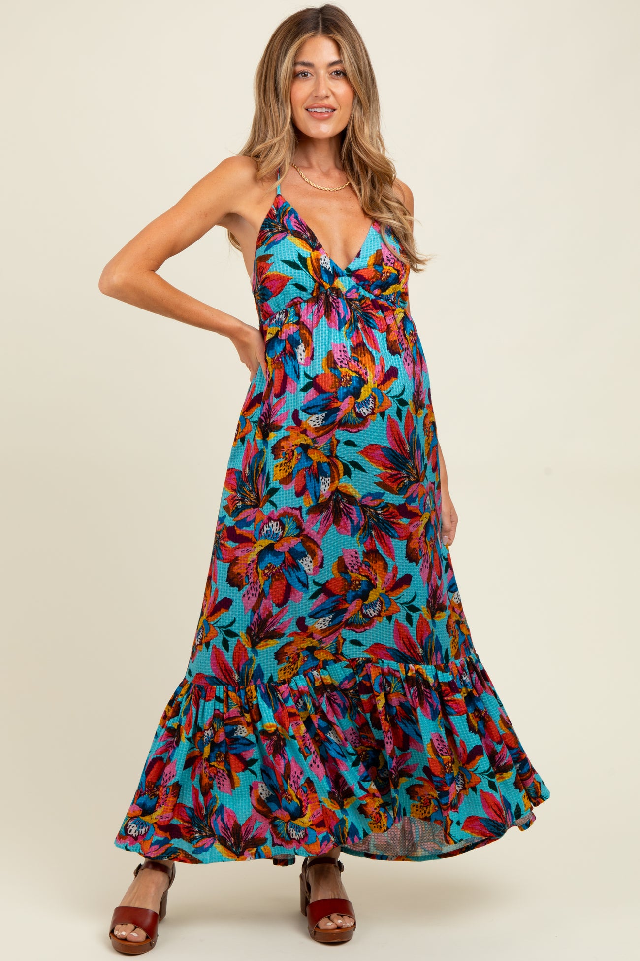 woman wearing a colorful floral maxi maternity dress with a ruffled hem and a visible baby bump