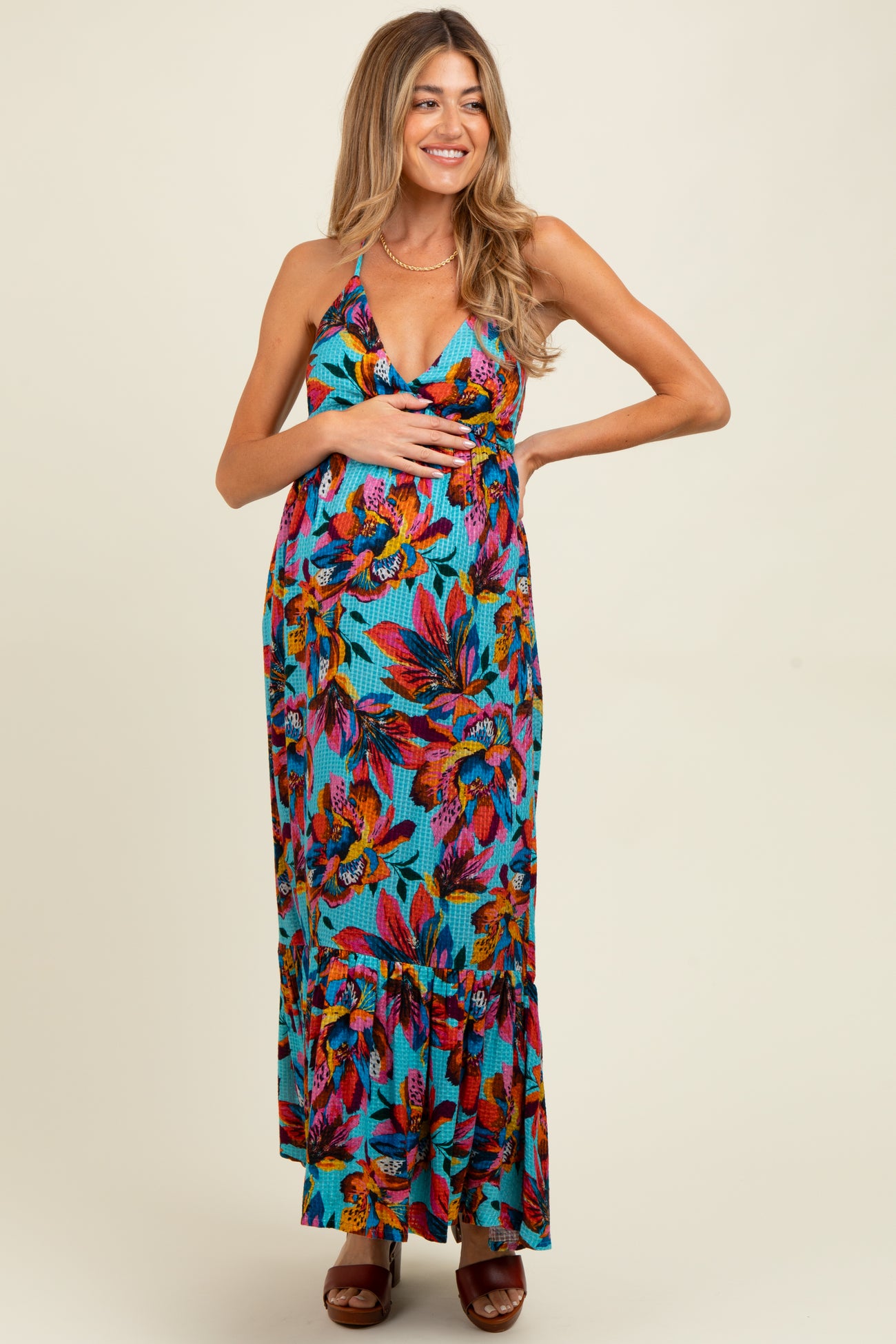 woman wearing a colorful floral maternity maxi dress and holding her baby bump