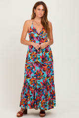 woman wearing a vibrant floral print maxi dress with a halter neckline and tiered hem