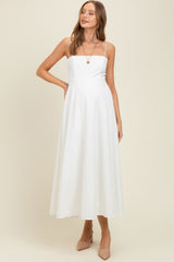 woman wearing a white maternity dress with a square neckline and flowy skirt, showcasing her baby bump