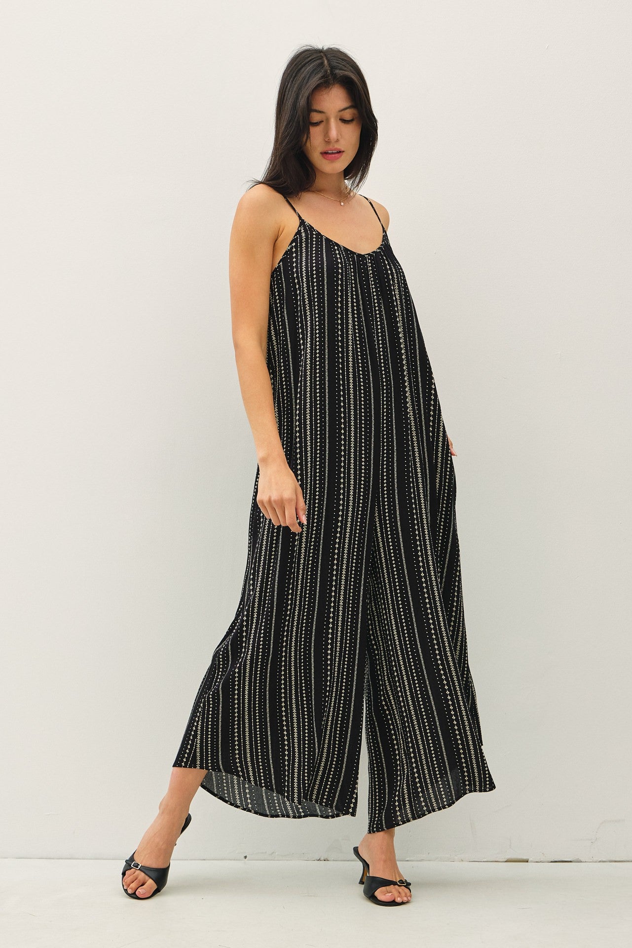 woman wearing a black and white striped spaghetti strap jumpsuit with loose fit and wide legs