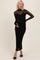 woman wearing a black maternity dress with sheer long sleeves and a fitted silhouette showcasing her baby bump