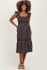 woman wearing a black floral print maternity dress with ruffle straps and a tiered skirt, showcasing her baby bump