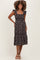 woman wearing a black floral print maternity dress with ruffle straps and a tiered skirt, showcasing her baby bump
