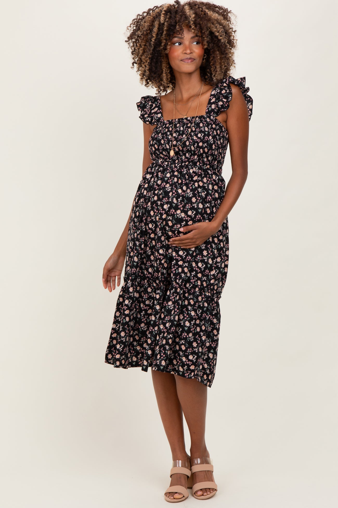 woman wearing a black floral maternity dress with ruffle straps and a visible baby bump