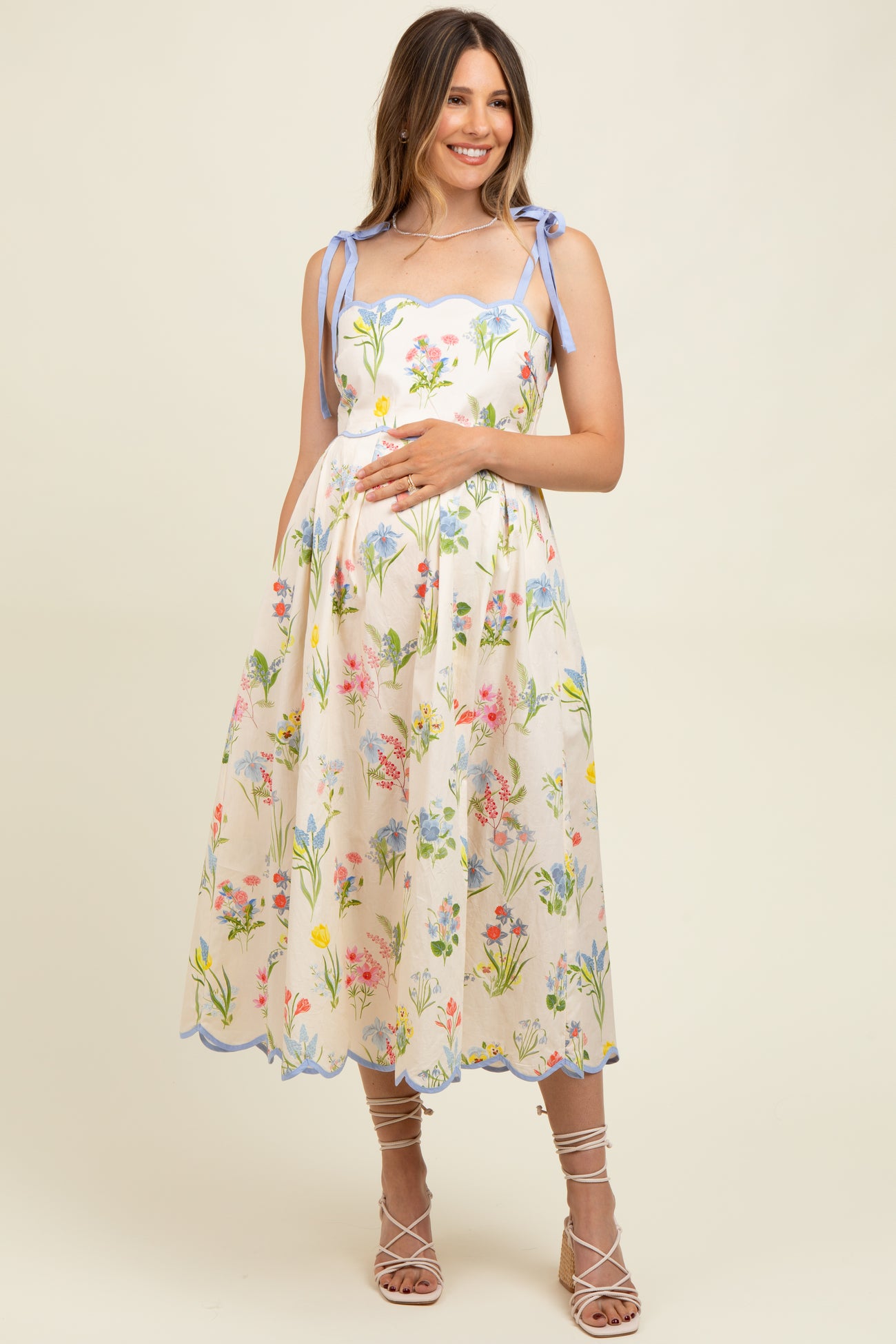 woman wearing a floral print sleeveless maternity dress with tie straps and a visible baby bump