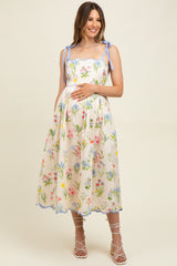 woman wearing a floral print sleeveless maternity dress with tie straps and a visible baby bump