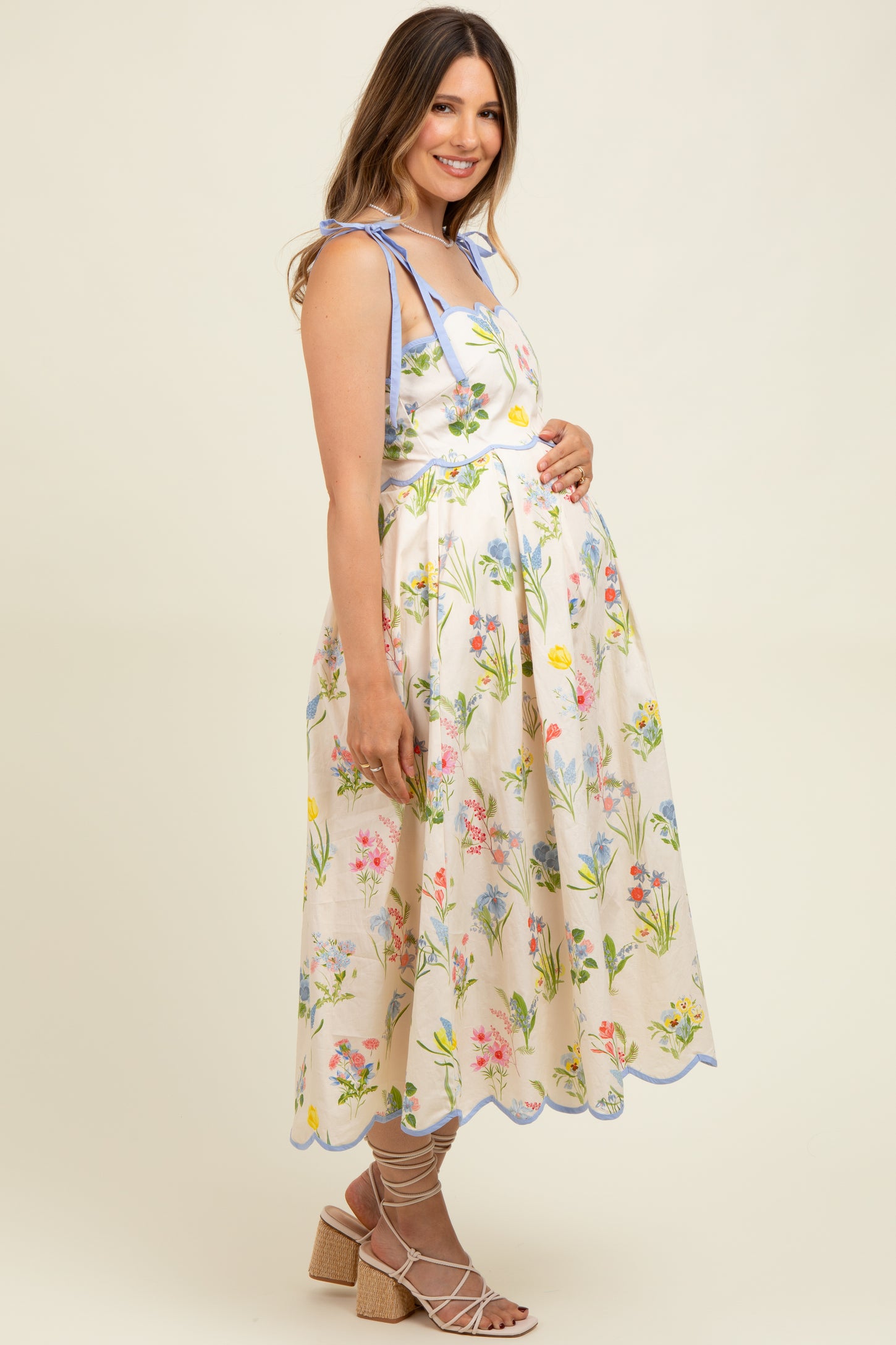 woman wearing a floral print maternity dress with blue accents and a visible baby bump