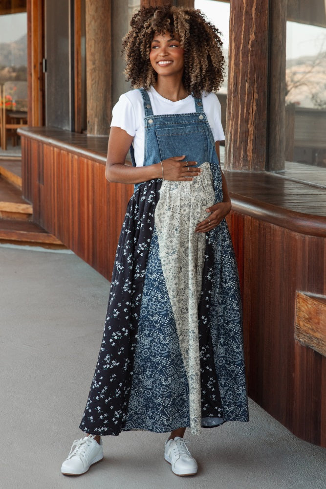 woman wearing a denim overall dress with a patterned skirt, showing her baby bump in a maternity wear setting