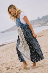 woman wearing a denim and printed maxi dress while walking on the beach