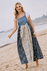 woman wearing a denim patchwork maxi dress with floral and patterned panels, standing on the beach