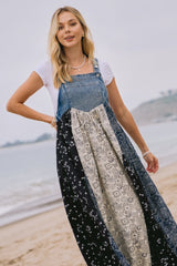 woman wearing a denim and patterned maxi dress with a white t-shirt underneath, standing on the beach