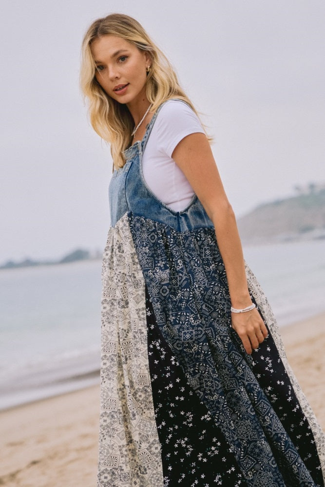 woman wearing a denim and patterned maxi dress standing on the beach with water in the background