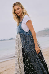 woman wearing a denim and patterned maxi dress standing on the beach with water in the background