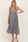 woman wearing a black and white gingham maternity dress with ruffled sleeves and a tiered hem, showing her baby bump