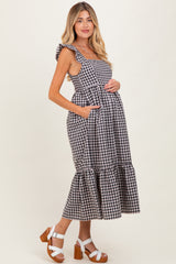 woman wearing a black and white gingham maternity dress with ruffled straps and a tiered skirt, holding her baby bump