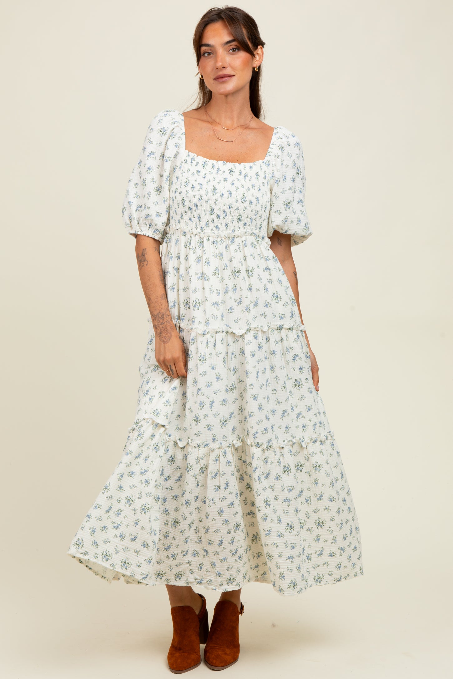 woman wearing a white floral maxi dress with puff sleeves and a tiered skirt
