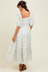 woman wearing a white floral maxi dress with puff sleeves and a smocked bodice, shown from the back