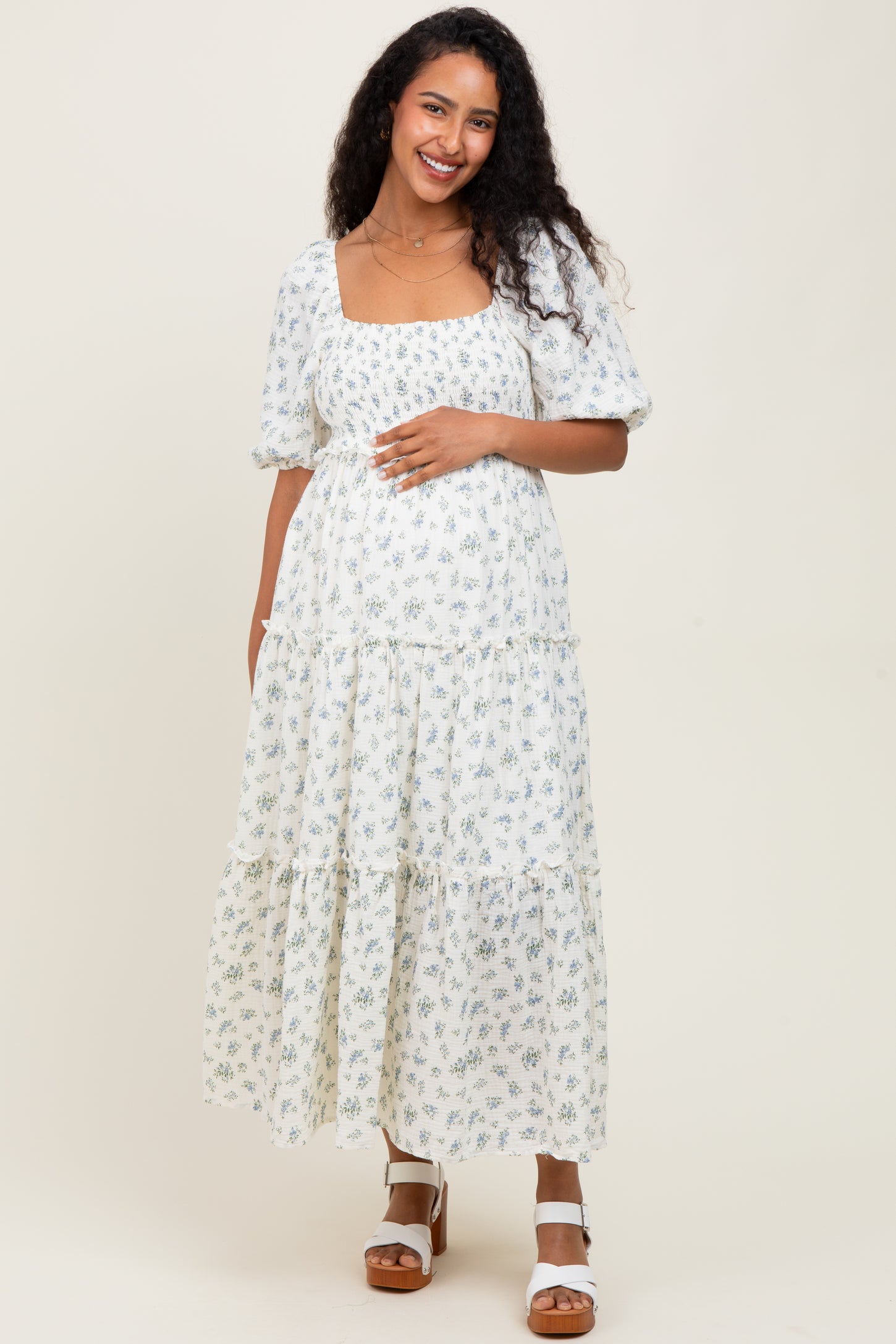woman wearing a floral print maternity maxi dress with puff sleeves and a visible baby bump